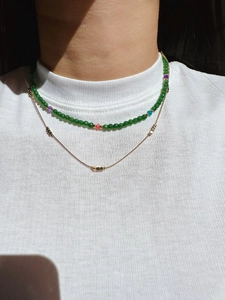 Double-layered necklace with green faceted beads and gold chain worn by a model