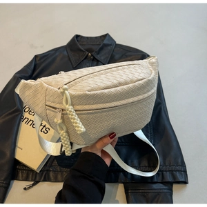 Detail of cream woven crossbody bag with matching zipper pull and adjustable wide strap