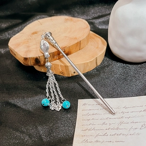 Detail of silver fish tassel hairpin with turquoise beads and intricate ethnic metalwork