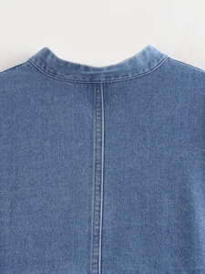 Detail of blue denim jacket showing high-density twill fabric and orange stitching