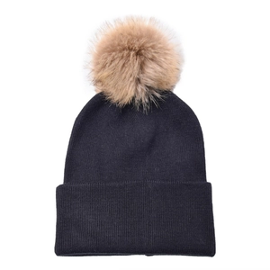 Detail of a black knit beanie featuring a large detachable light brown faux fur pom pom