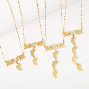 Macro detail of four gold MOM necklaces with heart stones and baby feet pendants