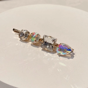 Detailed macro of gold hair clip featuring four colorful rhinestones in varied shapes