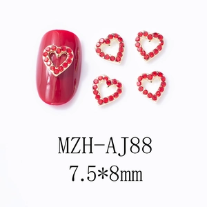 Détail macro de breloques à ongles coeur rouge avec base dorée et strass, taille 7,5x8mm