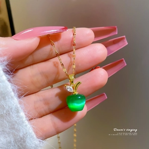Macro shot of gold apple necklace featuring green opal stone and sparkling zircon leaf