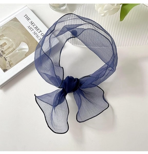 Detail of navy organza skinny scarf with black stitched edges on a decorative white desk