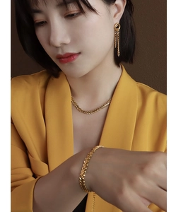 Detail shot of 18k gold leaf-textured jewelry set with necklace, bracelet and earrings