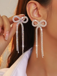 Close-up of sparkling bow tassel earrings with crystals on female model