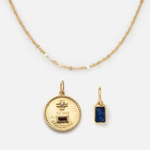 Detail of gold necklace with round red gem pendant and rectangular blue zircon charm