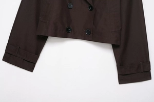 Detail of dark brown double-breasted coat showing black buttons and premium fabric texture