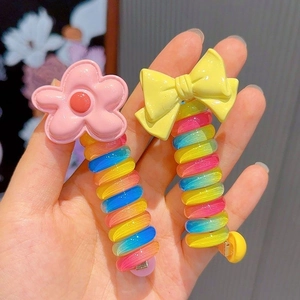 Detailed view of colorful spiral hair ties with pink flower and yellow bow decorations