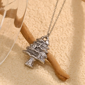 Close-up of a silver stainless steel Christmas tree pendant on a wooden stand