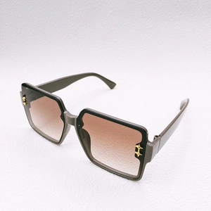 Detail of square oversized sunglasses with brown gradient lenses and gold star rivets