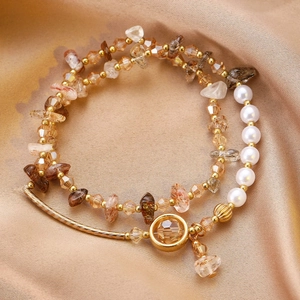Détail du bracelet doré avec citrine et perles sur satin de couleur champagne