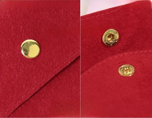 Détail d'une pochette à bijoux en velours rouge avec un bouton pression en métal doré