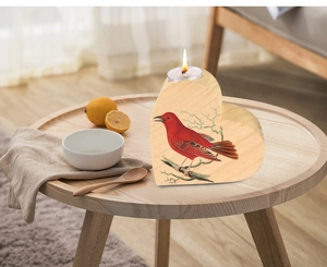 Close-up of heart-shaped wooden candle holder with red bird print and warm lit tea light