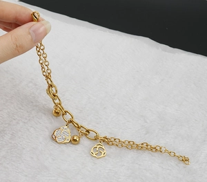Detail of gold double-layered bracelet featuring hollow rose pendants with zircon stones