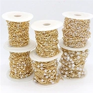 Macro shot of assorted gold and silver DIY jewelry chains with white pearls on spools