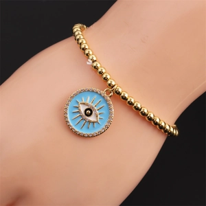 Gros plan d'un bracelet en perles dorées avec pendentif œil bleu et zircons brillants