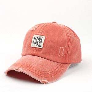 Detail der gewaschenen orangefarbenen Baseballkappe mit Maria-Stickerei und Used-Look