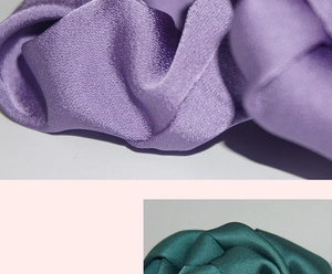 Detailed view of glossy satin fabric pleats in purple and dark green hair scrunchies