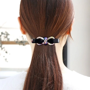 Elegant purple marble bow hair clip with rhinestones worn on black hair for women