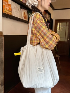 Japanese style white pleated tote bag with yellow straps shown in a cozy bookstore setting