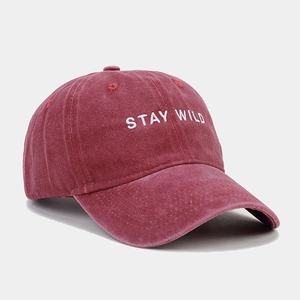 Close-up of Stay Wild white embroidery on washed red cotton vintage baseball cap