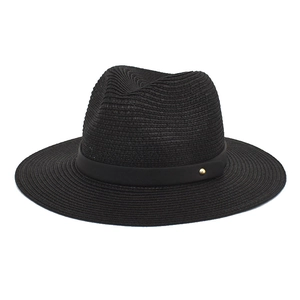 Close-up of black paper straw hat with woven texture and a gold metal rivet detail
