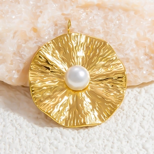 Detailed close-up of a round gold pendant with hammer texture and a white pearl inlay