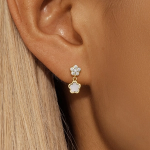 Macro shot of gold S925 sterling silver flower earrings with white shell and diamonds