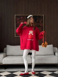Felpa rossa casual con stampa di bambola russa e tasca frontale su un divano grigio