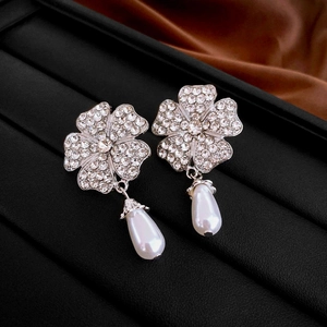 Macro shot of silver flower earrings with pavé crystals and white teardrop pearls