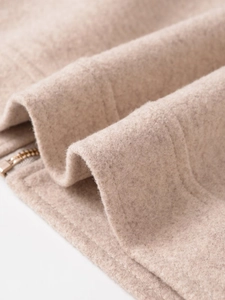 Detailed macro view of soft beige wool fabric texture and metal zipper closure