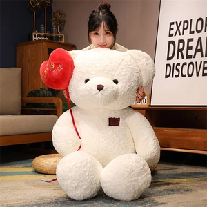 Close-up of a large white plush teddy bear being held by a model in a warm home setting
