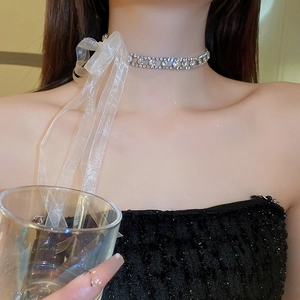 Detail der silbernen Strass-Halskette mit eleganter weißer transparenter Schleife am Model