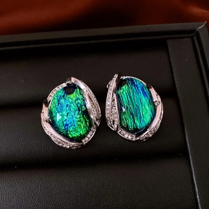 Macro shot of vintage resin earrings with blue-green iridescent stone and silver micro-pave