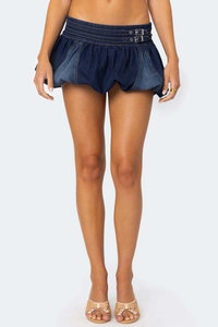 Détail d'une jupe bulle en denim bleu foncé à taille basse et boucles métalliques