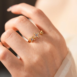 Macro shot of a golden open ring with purple zircon butterfly charms on a finger