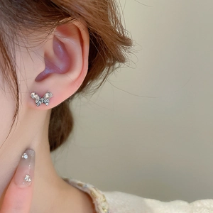 Detailed view of silver butterfly stud earring with sparkling crystals on a model's ear