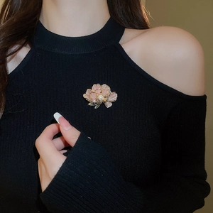 Detail of pink enamel flower brooch with pearl and zircons on black knitwear
