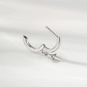 Polished silver star hoop earring with a cross pendant on a white fabric background
