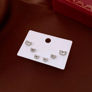 Detail of six silver bear stud earrings with cubic zirconia on deep brown satin fabric