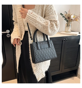 Détail du sac bandoulière noir gaufré avec sangle réglable porté par un mannequin