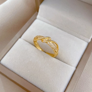 Polished gold plated wavy crisscross ring with cubic zirconia on velvet background