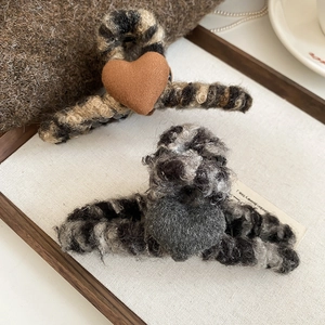 Gros plan de pinces à cheveux en peluche en forme de cœur marron et gris sur plateau