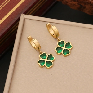 Golden hoop earrings with green four-leaf clover pendant on a minimalist beige background