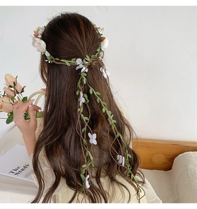 Close-up of white floral headband with realistic flowers and butterfly accents on hair