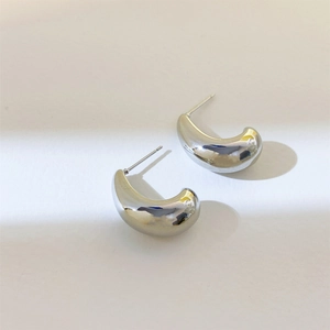 Detailed close-up of silver-tone C-shaped curved earrings with polished metallic luster
