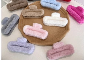 Nine assorted colors of plush rectangle shark hair clips displayed on a wooden tray